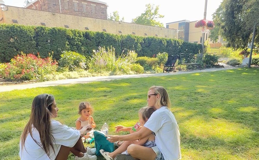 Our family sharing a picnic snack on the grass in a Stratford garden